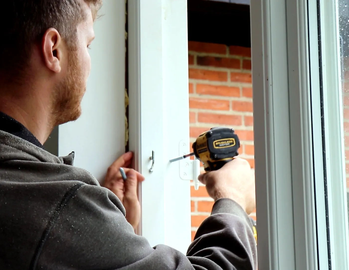Tradesperson drilling and fitting a window