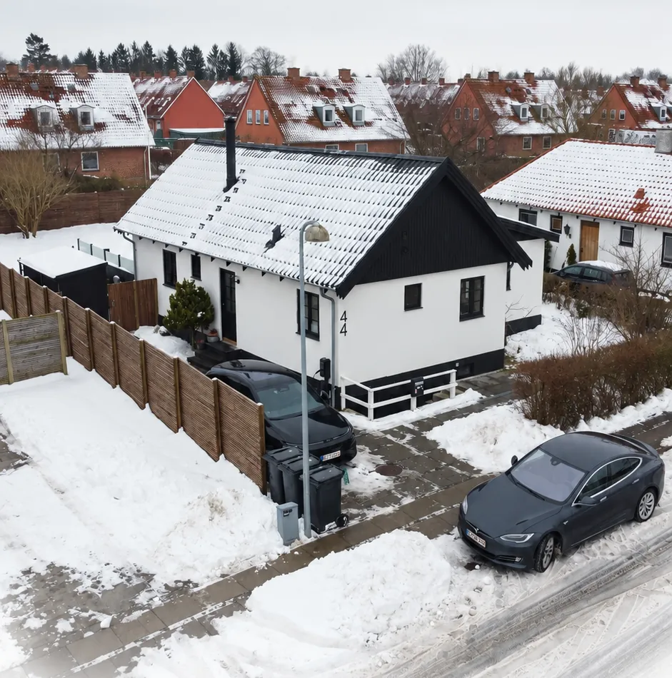 White house with black windows and snow on the roof in a Danish residential neighbourhood on a winter day